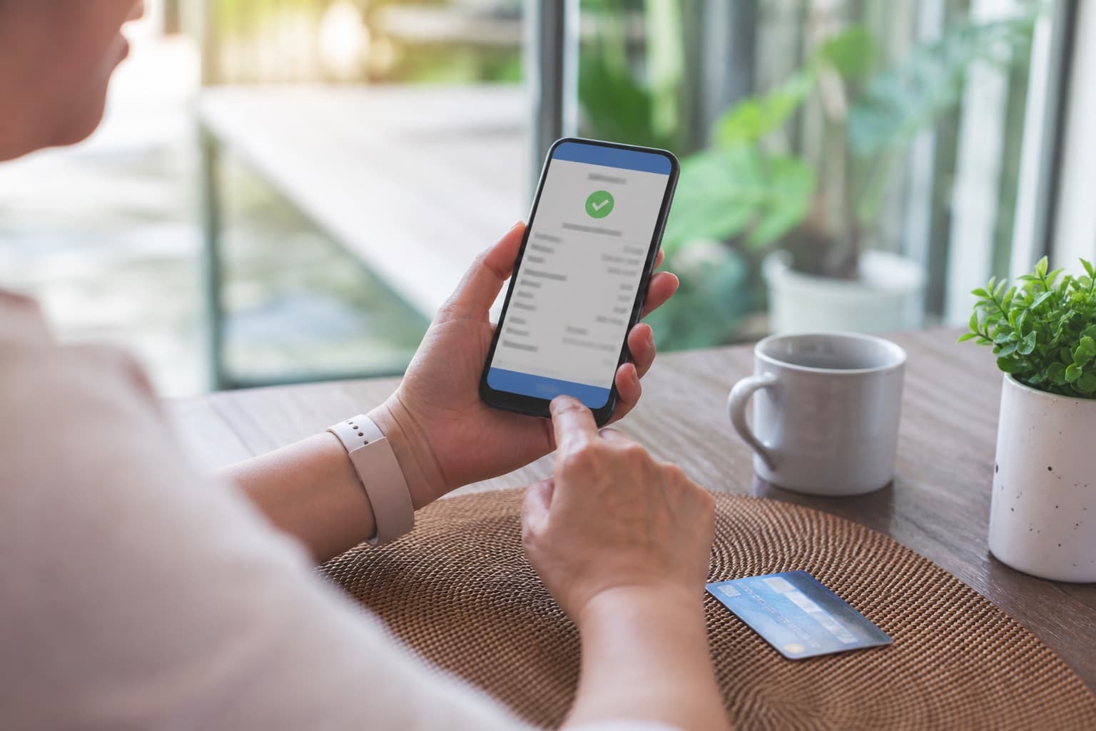 Homeowner reviewing a lawn care invoice on a phone at the kitchen table